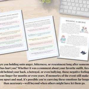 May include: Three white papers with text on a wooden surface. The papers are titled "Tips to Letting Go of Grudges", "How Grudges Affect Your Mind and Body", and "Holding a Grudge". A keyboard and plant are in the background. Text at the bottom reads: "Are you holding onto anger..."