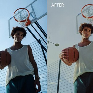 May include: A person wearing a white tank top and dark blue shorts holds a basketball in front of a basketball hoop. The hoop is attached to a metal pole and net. The background is a blue sky and a chain link fence.