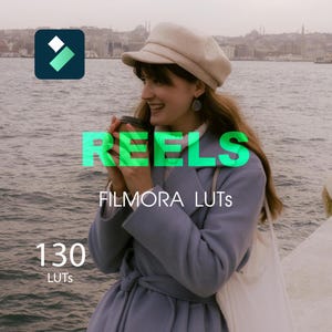 Puede incluir: Una mujer con un abrigo azul claro y un sombrero beige, sosteniendo una taza de café. La imagen incluye el texto "REELS", "FILMORA LUTS" y "130 LUTS". El logotipo de Filmora está en la esquina superior izquierda, con un cuerpo de agua y una ciudad al fondo.