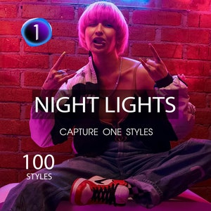 May include: A person wearing a pink wig and a black and white jacket poses in front of a brick wall with neon lights. The text "NIGHT LIGHTS CAPTURE ONE STYLES 100 STYLES" is visible in the image.