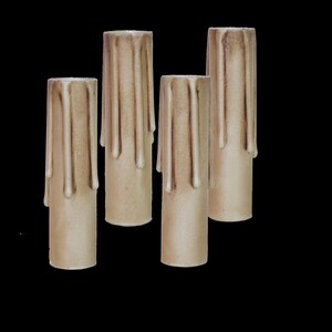 May include: Four beige candle sleeves with a dripped wax design. The sleeves are made of a textured material and are designed to fit over a standard candle.