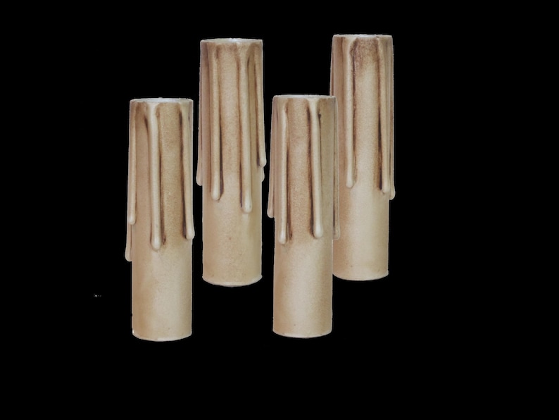 May include: Four beige candle sleeves with a dripped wax design. The sleeves are made of a textured material and are designed to fit over a standard candle.