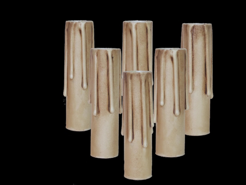 May include: Set of six beige candle sleeves with a drippy wax design. The sleeves are made of a textured material and are designed to fit over a standard candle.