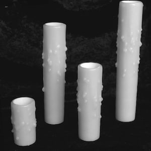 May include: Four white pillar candles with a textured design. The candles are different sizes.
