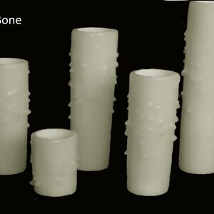 May include: Five white candles with a textured surface. The candles are different sizes and are arranged in a row. The text "Bone" is visible in the top left corner of the image.