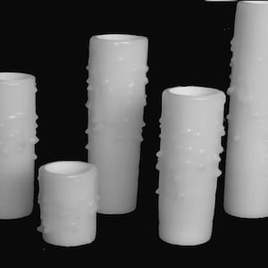 May include: Five white pillar candles with a textured surface. The candles are different sizes.