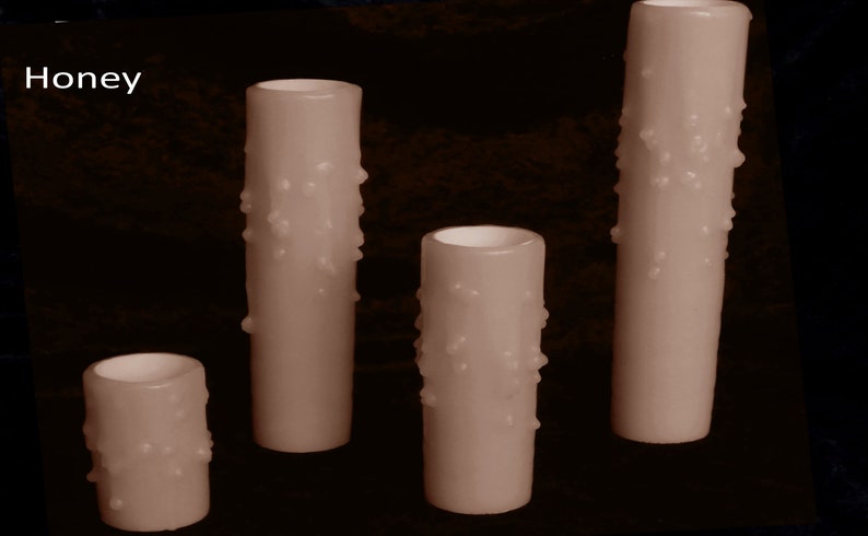 May include: Four honey-colored candles with a textured, star-shaped design. The candles are different sizes and are arranged in a row from tallest to shortest.