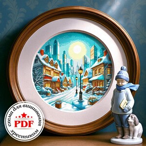 Peut inclure: Une œuvre d'art au point de croix encadrée représentant une scène hivernale enneigée avec une rue bordée de maisons et des gratte-ciel en arrière-plan. Le cadre est rond et marron. Une figurine d'enfant en vêtements d'hiver est à côté.