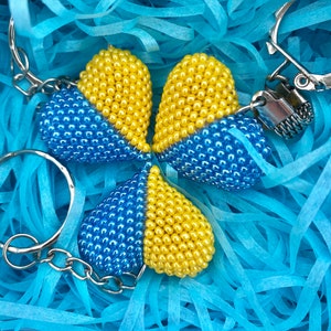 May include: Three beaded heart-shaped keyrings in blue and yellow. The keyrings are attached to a silver ring.