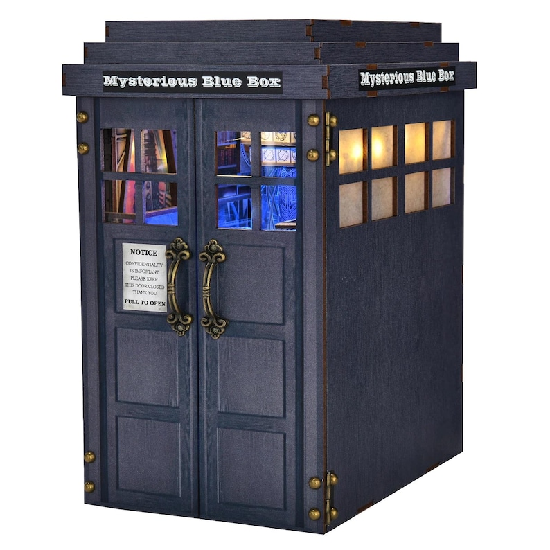 Puede incluir: Una caja de madera azul marino con el texto "Mysterious Blue Box" en la parte superior. La caja tiene puertas dobles con manijas ornamentadas y una peque&ntilde;a ventana. El texto "NOTICE" y "PULL TO OPEN" es visible en la puerta.