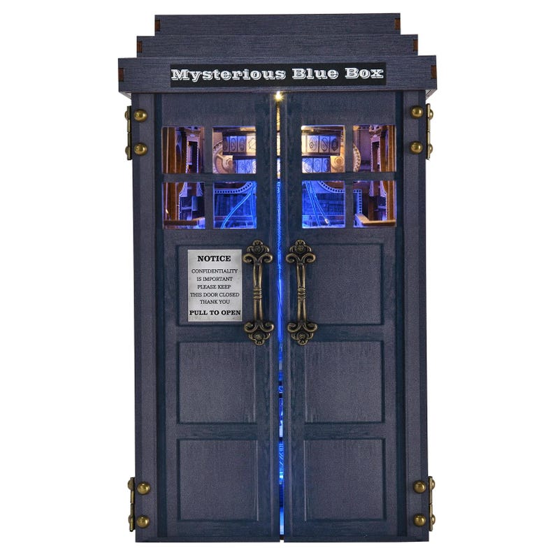 Puede incluir: Una caja de madera azul con el texto "Mysterious Blue Box" en la parte superior. La caja tiene dos puertas con manijas ornamentadas y un letrero que dice "Notice Confidentiality is Important Please Keep This Door Closed Thank You Pull to Open."