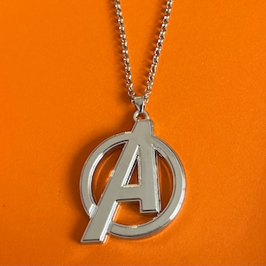 Op de afbeelding: Zilveren ketting met een hanger met het Avengers-logo. Het logo is een gestileerde "A" in een cirkel.