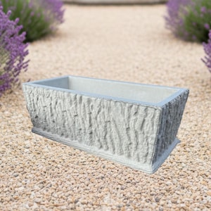 May include: A rectangular light gray planter with a textured exterior surface that mimics the appearance of tree bark. The planter features a smooth, flat rim and a hollow interior, designed with a tapered shape that narrows toward the base.