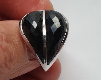 May include: A silver ring with a black heart-shaped gemstone. The gemstone is faceted and has a silver band.