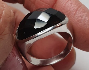 May include: A silver ring with a large, black, faceted gemstone.