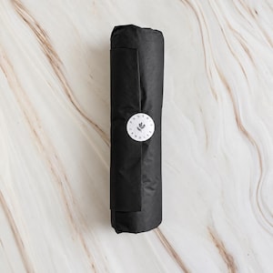 A black cylindrical object with a white circular label on it, placed on a marble surface.