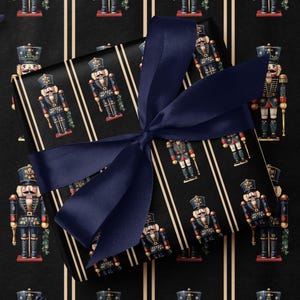 May include: Black wrapping paper with a pattern of toy nutcrackers in blue, red, and gold, with a navy blue ribbon tied around a gift box. The background features a repeating pattern of nutcrackers and vertical stripes.