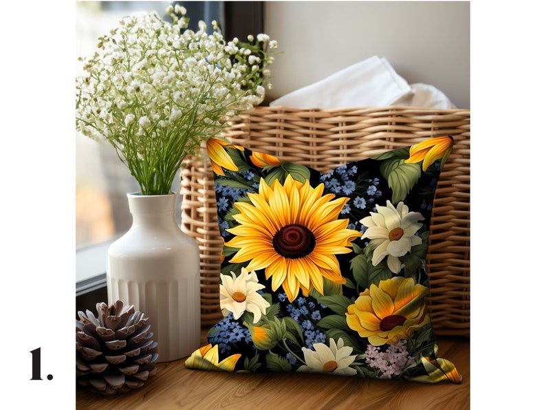 Puede incluir: Una almohada negra con un dise&ntilde;o floral con girasoles, margaritas y flores azules. La almohada est&aacute; sobre una superficie de madera con una cesta de mimbre y un jarr&oacute;n de flores blancas en el fondo.