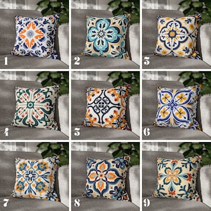 May include: Nine different throw pillow designs featuring a colorful geometric pattern inspired by traditional Spanish tiles. The pillows are all square and have a white background with blue, yellow, orange, and red accents.