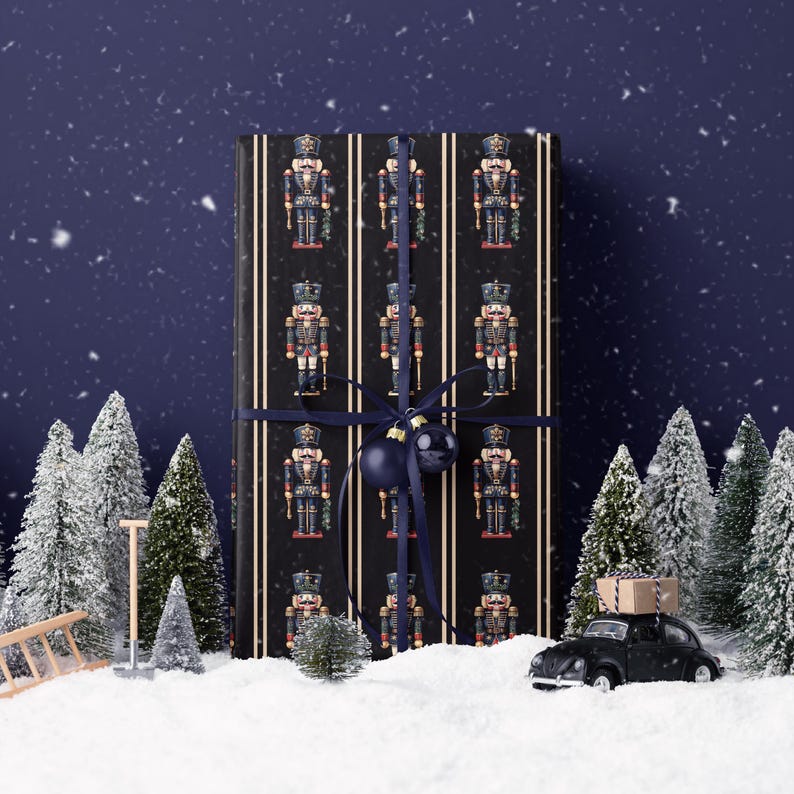 May include: A wrapped gift with a black background and a pattern of toy nutcrackers. The gift is tied with a navy blue ribbon and a matching ornament. The scene is set in a snowy landscape with miniature Christmas trees and a vintage car.
