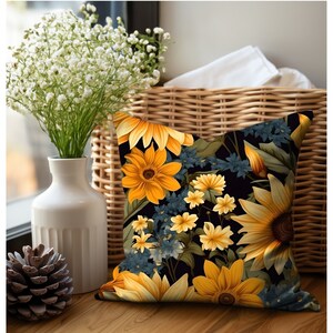 Puede incluir: Una almohada negra con un patr&oacute;n floral con girasoles amarillos y flores azules sobre un fondo negro.
