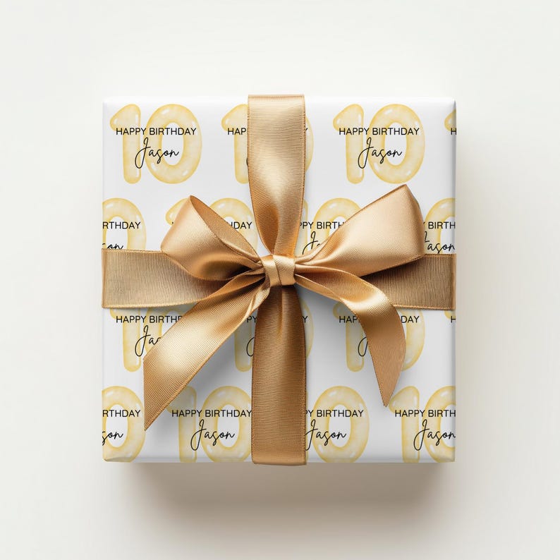 Może przedstawiać: Prezent urodzinowy owinięty w biały papier, z powtarzającym się wzorem liczby 10 w kolorze ż&oacute;łtym, słowami "Happy Birthday" i imieniem "Jason". Jest zawiązany złotą wstążką.