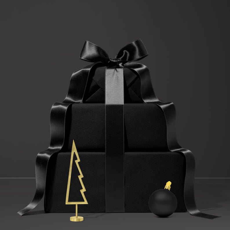 May include: A stack of wrapped black gift boxes with a large black satin bow and ribbon. A gold-colored metal Christmas tree and a black ornament with a gold top are in front of the gifts. The background is a dark gray.