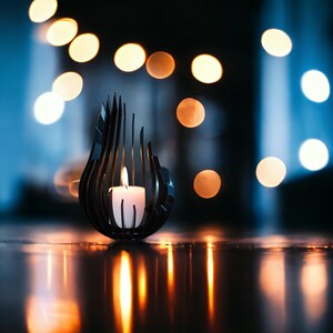 May include: A black metal candle holder shaped like a flame with a white candle inside. The candle holder is on a dark surface with a blurry background of warm white lights.