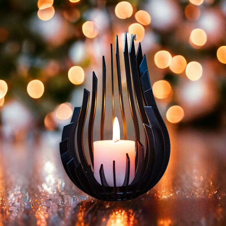 May include: A black metal candle holder with a geometric design, holding a white candle. The candle holder is on a reflective surface with a blurred background of lights.