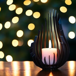 May include: A black metal candle holder shaped like a flame with a white candle inside. The candle holder is on a wooden surface with a blurred background of lights.