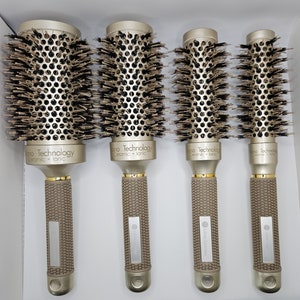 May include: Four professional hair styling brushes. Each brush has a gold-colored barrel with black bristles and a textured, taupe-colored handle. The text "Nano Technology Ceramic + Ionic" is printed on the barrel. The brand name "Lilian Sanchez" is printed on the handle.