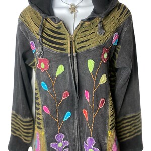 Peut inclure: Une veste à capuche noire avec une fermeture éclair et des broderies florales colorées. La veste présente des accents vert olive et noirs, une capuche à cordon et des manches longues. Le design comprend des fleurs et des feuilles appliquées de différentes couleurs.