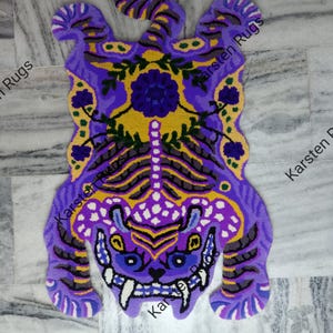 May include: Purple and yellow tiger rug with floral details. The rug is made of wool and has a shaggy texture.