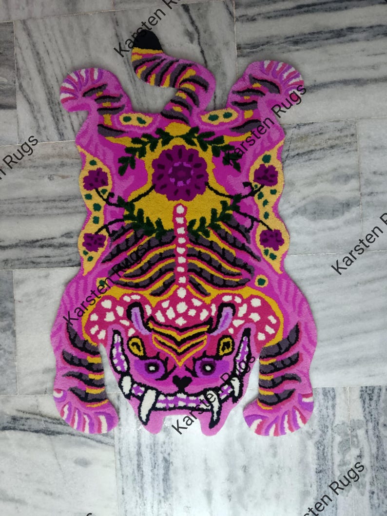 May include: A pink and yellow tiger rug with floral details. The rug is made of a soft, plush material and features a detailed design of a tiger with a fierce expression. The rug is perfect for adding a touch of whimsy and personality to any room.