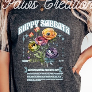 Puede incluir: Una camiseta gris oscuro con un dise&ntilde;o floral y el texto "Happy Sabbath" en una fuente retro. El dise&ntilde;o tambi&eacute;n incluye el texto "Exodus 20:8-11" y "Remember the Sabbath Day".