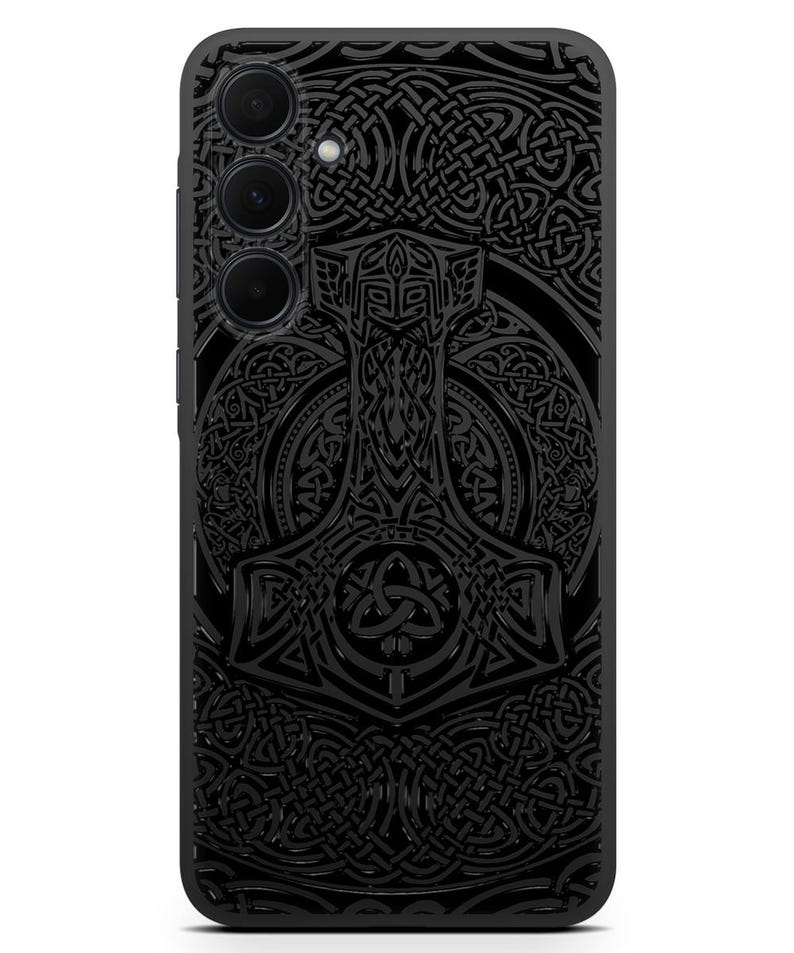 May include: Black phone case with a detailed design of a hammer and intricate knotwork. The design is in a dark gray color and has a 3D effect.