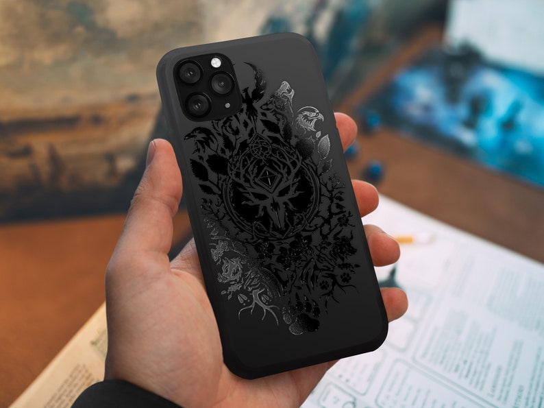 Puede incluir: Carcasa de tel&eacute;fono negra con un dise&ntilde;o detallado de un &aacute;rbol con ramas, hojas y animales. El dise&ntilde;o es de color gris oscuro y tiene un aspecto texturizado.