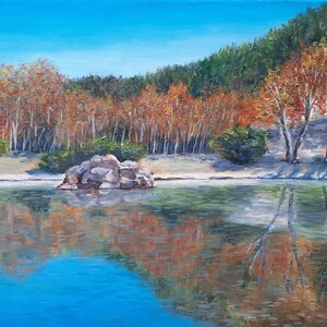 以下が含まれることがあります： 真ん中に岩の島がある湖の絵。湖はオレンジ、イエロー、レッドの秋の紅葉をした木々に囲まれています。空は青く、水は濃い青です。