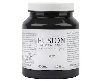 Może przedstawiać: Czarna plastikowa butelka farby mineralnej Fusion w kolorze Popiół. Butelka jest oznaczona nazwą marki, nazwą produktu i kolorem. Butelka zawiera 500 mililitrów (16,9 uncji płynu) farby.
