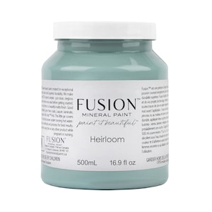 May include: A 16.9 fluid ounce bottle of Fusion Mineral Paint in the color Heirloom. The paint is a light blue-green color. The bottle is labeled with the Fusion Mineral Paint logo and the words "paint it beautiful".