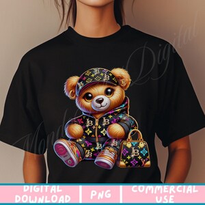 May include: A black t-shirt with a cartoon teddy bear wearing a black and gold patterned outfit and a black and gold patterned hat. The teddy bear is holding a black and gold patterned handbag.
