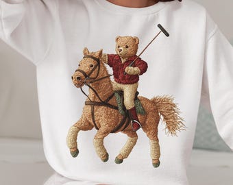 May include: White sweatshirt with a graphic of a brown teddy bear riding a brown horse while holding a polo mallet.