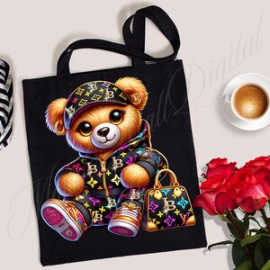 May include: Black tote bag with a cartoon teddy bear wearing a black and white patterned hoodie, a black and white patterned hat, and holding a black and white patterned handbag. The teddy bear has brown fur and big brown eyes.