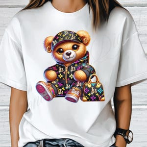 May include: White t-shirt with a cartoon teddy bear wearing a black and white patterned jacket, a black and white patterned hat, and holding a black and white patterned handbag.