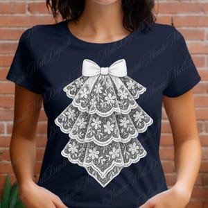 May include: Navy blue t-shirt featuring a white, layered lace design with a bow at the top. The lace design is detailed with floral patterns, creating a vintage or Victorian aesthetic. The t-shirt is a classic crew neck style.