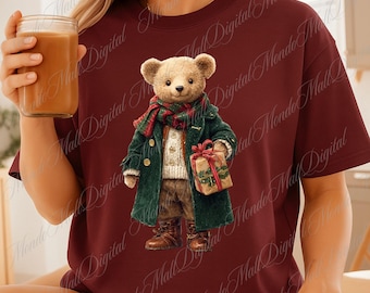 May include: Burgundy t-shirt with a detailed illustration of a teddy bear wearing a green coat, scarf, and holding a wrapped gift. The bear is wearing brown boots. The shirt has the words "Mondo Mall Digital" printed on it.