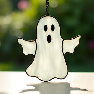 May include: A white stained glass ghost with black outlines and a black mouth hanging from a chain. The ghost has two black eyes.