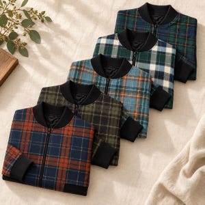 May include: Five bomber jackets arranged in a diagonal row, each featuring a distinct plaid pattern in color combinations of blue and orange, olive and black, teal and brown, green and white, and dark green and blue, all with black ribbed collars.