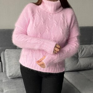 May include: A soft, pink, fuzzy turtleneck sweater with a cable knit pattern.