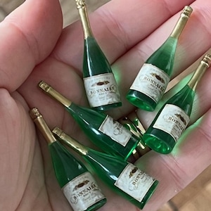 May include: Six miniature green glass champagne bottles with gold tops and labels that read "BONNAIRE" in white lettering.